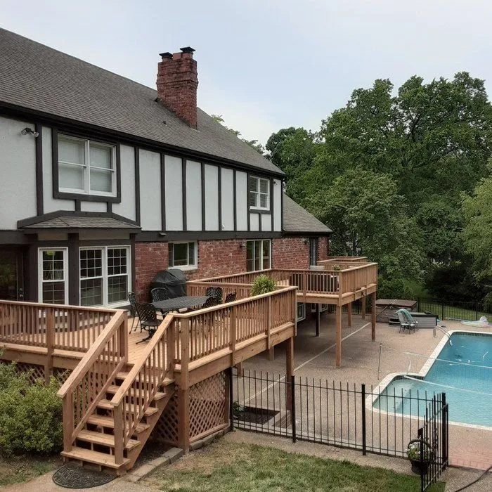 Large custom wood deck wrapping a Tudor brick home